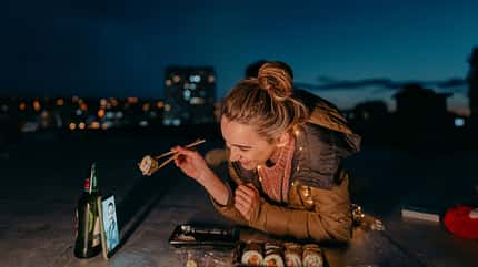Junge Frau hat nachts ein Sushi-Date über das Telefon Junge Frau hat nachts ein Sushi-Date über das Telefon