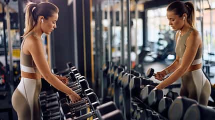 Frau greift Kurzhanteln im Gym Frau greift Kurzhanteln im Gym