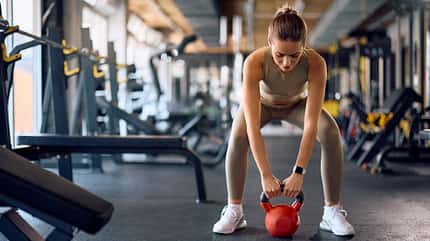 Frau macht Squats mit Kettlebell Frau macht Squats mit Kettlebell