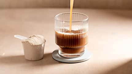 Glas mit kaltem Kaffee und Scoop Proteinpulver