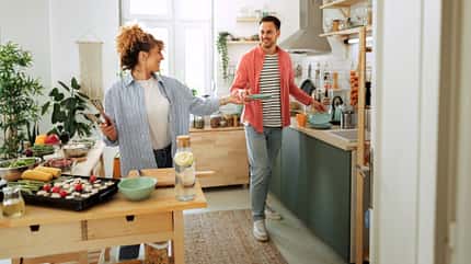 Lässig gekleidetes junges Paar, das zu Hause in der Küche frühstückt Lässig gekleidetes junges Paar, das zu Hause in der Küche frühstückt