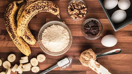 Schüssel mit Mehl, Bananen, Eiern und Zartbitterschokolade