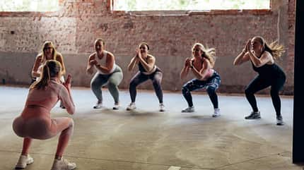 caucasian,slim,body,fit,loss,jumping squat,fitness,warming up,cl Rear,View,Of,A,Personal,Trainer,Giving,Gymnastics,Class,To