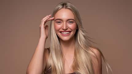 Eine Frau mit naturblonden Haaren lächelt in die Kamera 