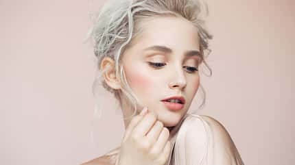 Eine Frau mit platinblonden Haaren vor rosa Hintergrund
