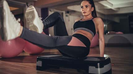 Junge Frau trainiert auf einem Step-Board im Gym