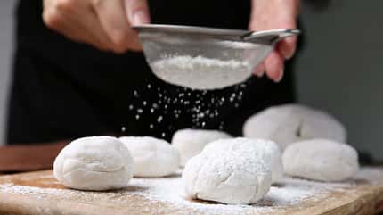 Frau bereitet Mochi-Eis zu und streut Mehl über die Mochis