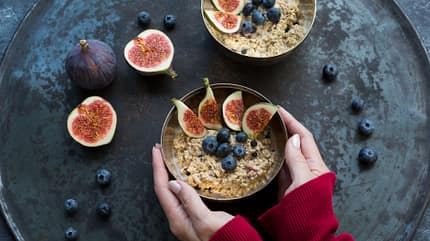 Eine Frau hält Schüssel mit Porridge und Feigen Eine Frau hält Schüssel mit Porridge und Feigen