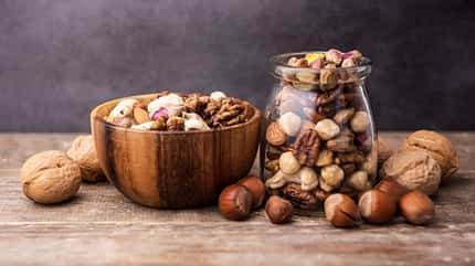Mixed nuts in a wooden bowl and glass bottle on old table Mixed nuts in a wooden bowl and glass bottle on old table