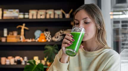 Eine Frau trinkt einen grünen Smoothie Eine Frau trinkt einen grünen Smoothie