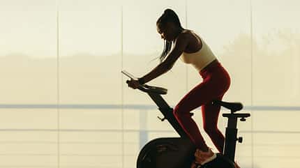 Woman engaging in an online fitness class with a stationary bike