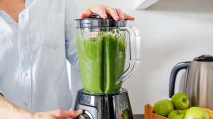 Eine Frau bereitet grünen Smoothie zu