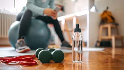 Eine Frau sitzt auf einem Fitnessball und schaut auf ihr Smartphone Eine Frau sitzt auf einem Fitnessball und schaut auf ihr Smartphone
