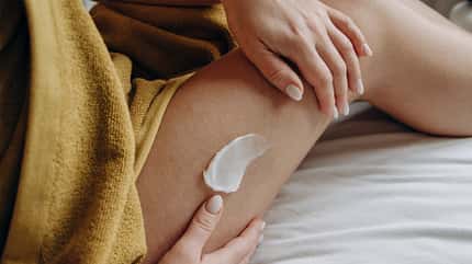 Eine Frau cremt sich ihr Bein ein Eine Frau cremt sich ihr Bein ein