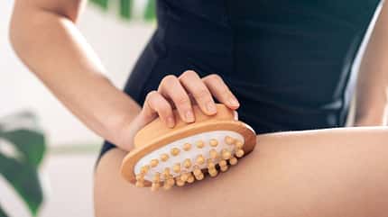 Eine Frau verwendet eine Trockenbürste auf ihrem Bein Eine Frau verwendet eine Trockenbürste auf ihrem Bein