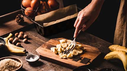 Eine Frau zermatscht Bananen mit einer Gabel