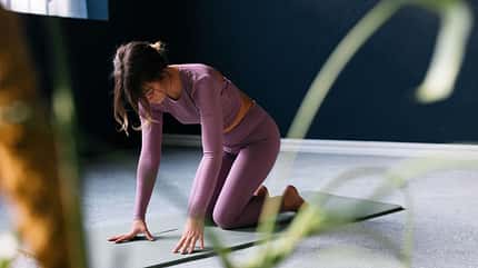 Woman Practicing Yoga on Mat in Minimalist Home Interior Woman Practicing Yoga on Mat in Minimalist Home Interior