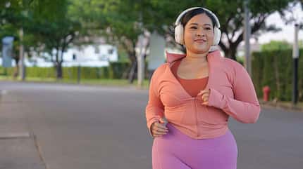 Eine kurvige Frau in pinker Sportkleidung beim Joggen Eine kurvige Frau in pinker Sportkleidung beim Joggen