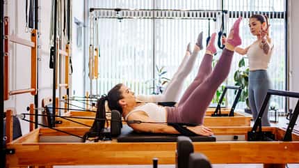 Eine Frau gibt Sportlerinnen Anweisungen beim Pilates-Training Eine Frau gibt Sportlerinnen Anweisungen beim Pilates-Training
