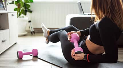 Eine Frau trainiert Russian Twists mit Kurzhanteln Eine Frau trainiert Russian Twists mit Kurzhanteln