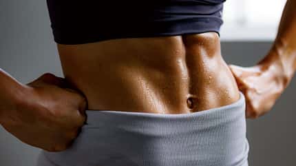 Nahaufnahme des verschwitzten Sixpacks einer trainierten Frau Nahaufnahme des verschwitzten Sixpacks einer trainierten Frau