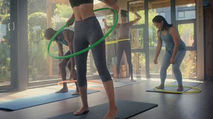 Mehrere Frauen, die auf Yogamatten mit Hula Hoop-Reifen trainieren