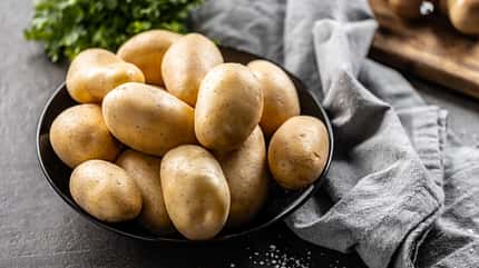 Rohe Kartoffeln in einer dunklen Schale Rohe Kartoffeln in einer dunklen Schale