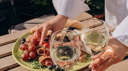 Eine Frau hält ein Weinglas und isst von einer Mezze-Platte