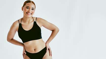 Eine Frau in schwarzer Unterwäsche vor hellem Hintergrund