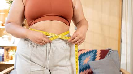 Eine kurvige Frau misst ihr Körperfett