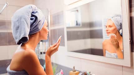 Woman cleaning her skin in bathroom.
