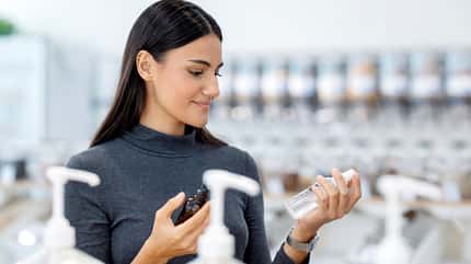 Eine Frau schaut sich verschiedene Cremes an 