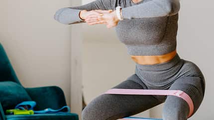 Eine Frau trainiert ihre Beine mit einem Powerband Eine Frau trainiert ihre Beine mit einem Powerband