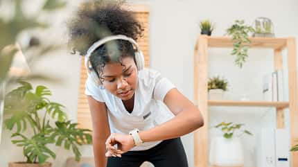 Feeling accomplished after a home workout, she checks her progress on her smartwatch.
