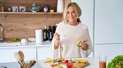 Eine ältere Dame bereitet Obstsalat in der Küche zu Eine ältere Dame bereitet Obstsalat in der Küche zu