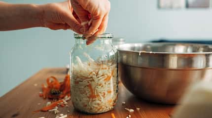 woman prepares pickled white cabbage, puts the cabbage in a glass jar. Fermented product. hands close-up woman prepares pickled white cabbage, puts the cabbage in a glass jar. Fermented product. hands close-up