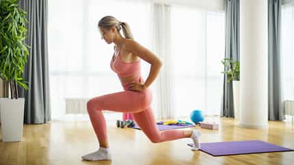 Junge Frau dehnt sich in einem hellen Raum.