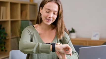 Eine Frau schaut beim Arbeiten auf ihre Fitnessuhr