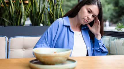 Frau sitzt im Restaurant und schaut nachdenklich in eine andere Richtung als zum Essen
