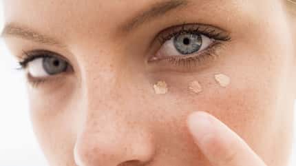 Frau trägt Concealer unter dem Auge auf Frau trägt Concealer unter dem Auge auf
