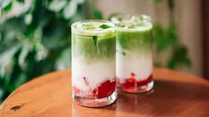 Zwei Iced Strawberry Matcha Lattes auf einem Tisch Zwei Iced Strawberry Matcha Lattes auf einem Tisch