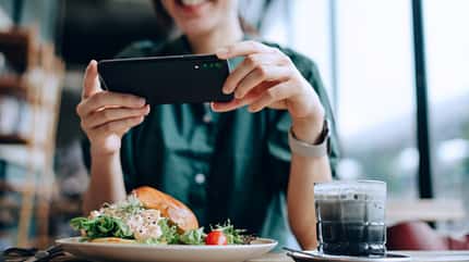 Eine Frau trackt ihre Mahlzeit mit einem Smartphone