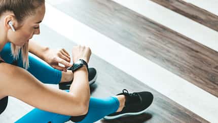 Frau in Sportklamotten bedient ihre Smartwatch