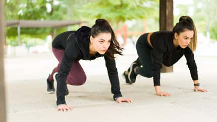 Zwei Frauen in dunkler Kleidung führen Mountain Climbers (Bergsteiger) aus.