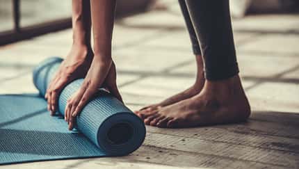 Frau rollt eine Yogamatte ein