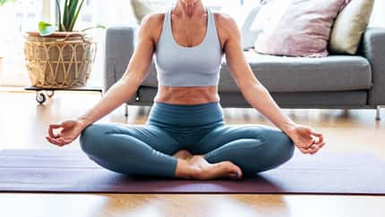 Ältere, sportliche Dame praktiziert Yoga auf einer Gymnastikmatte