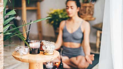 junge Frau praktiziert Yoga bei Kerzenlicht in gemütlicher Atmosphäre