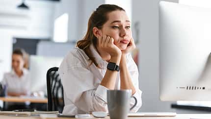 Bored,Young,Woman,Dressed,In,Shirt,Sitting,At,Her,Workplace