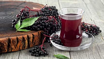Glas mit Holundersaft und Holunderbeeren