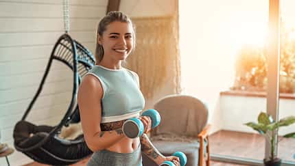 Determined,Woman,Losing,Weight,At,Home,And,Exercising,With,Dumbbells.